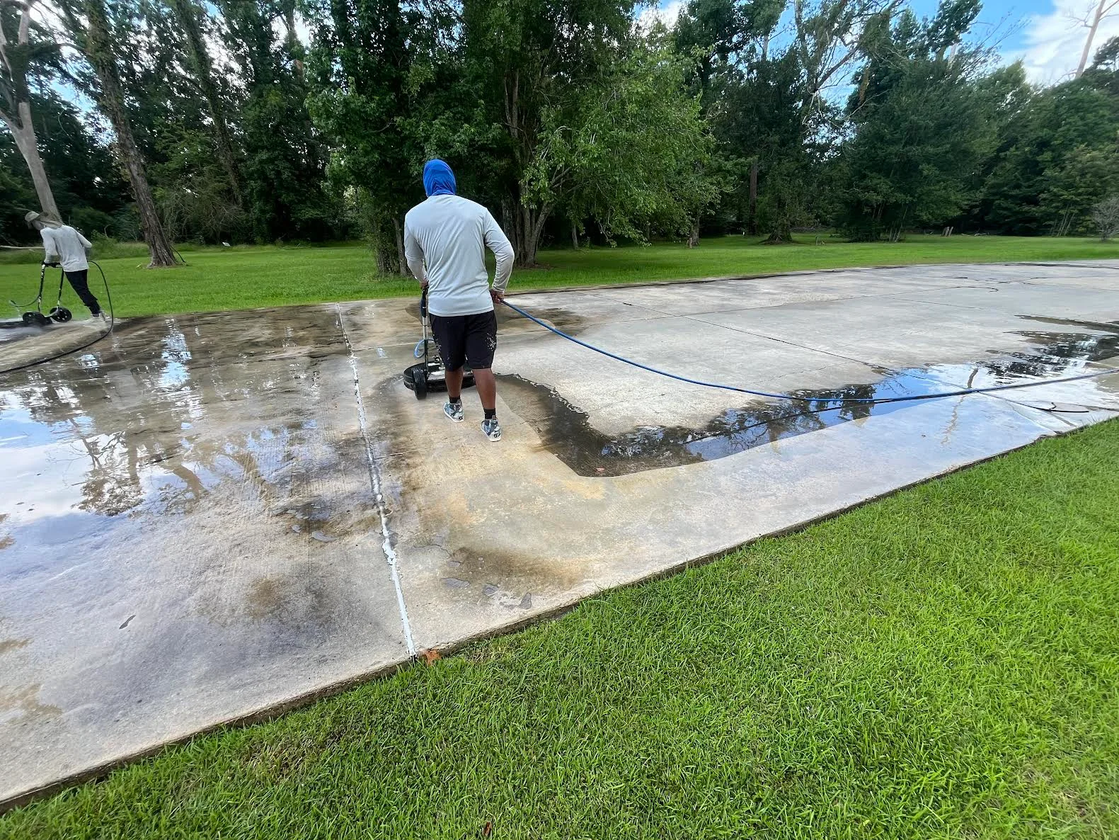 A ranch-style home in Satsuma, Alabama with a freshly pressure-washed concrete driveway and clean siding, showing the contrast between treated and untreated surfaces. Mold and algae staining has been removed from the exterior, leaving the surface visibly clear.