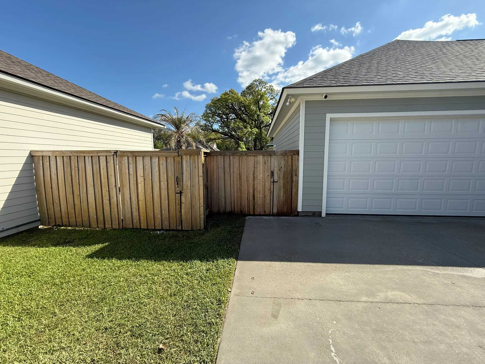 A wood deck in Satsuma, Alabama shown after soft wash cleaning, with mold and gray weathering removed and natural wood color restored. A privacy fence in the background shows the same clean result along the full surface.